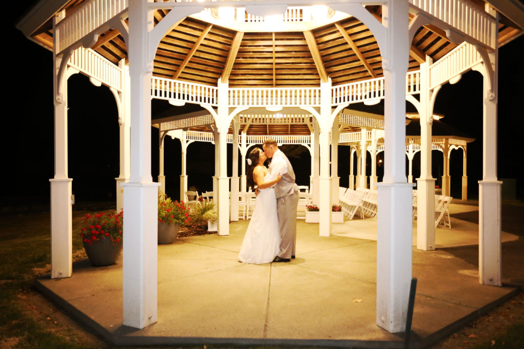 Bride and groom kissing under gazebo late at night