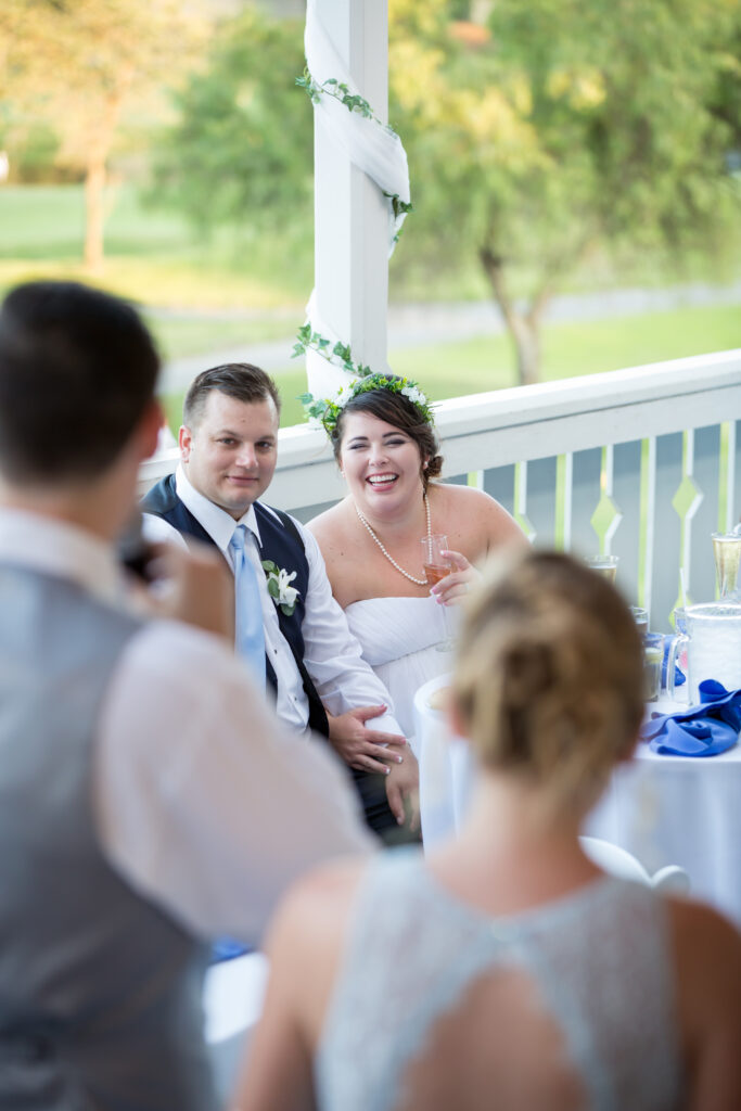 View of bride and groom as they listen to best man's toast